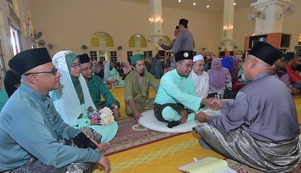 Majlis akad nikah beramai-ramai di Terengganu dengan pasangan pengantin dan jurunikah duduk di ruang masjid.