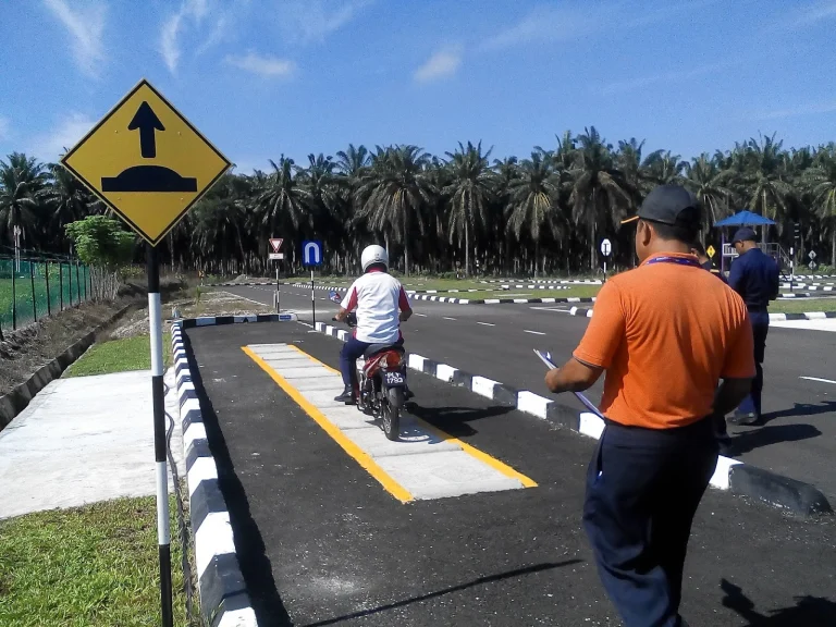 Peserta menjalani latihan menunggang motosikal di litar ujian lesen memandu dengan pemantauan pegawai.
